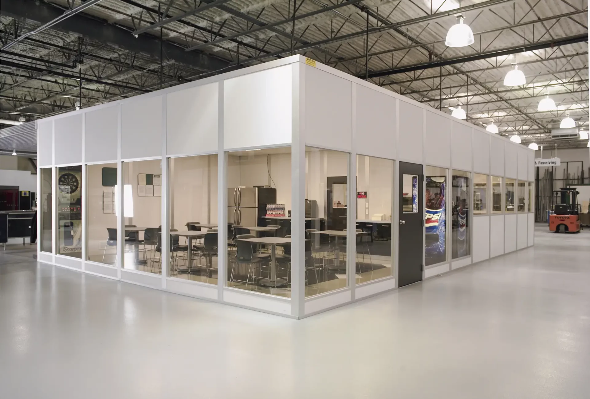 Modular break room inside warehouse with tables, chairs, and vending machine by Jarvis Material Handling
